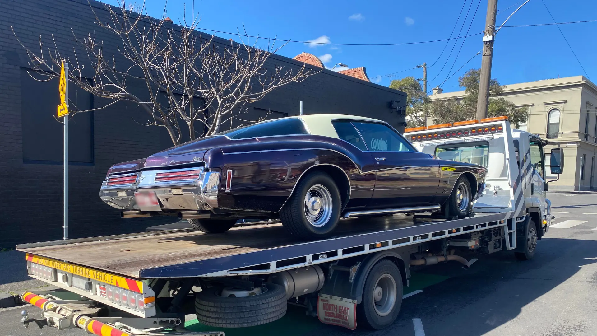 All Over Towing tilt tray loading a classic coupe on a Melbourne street