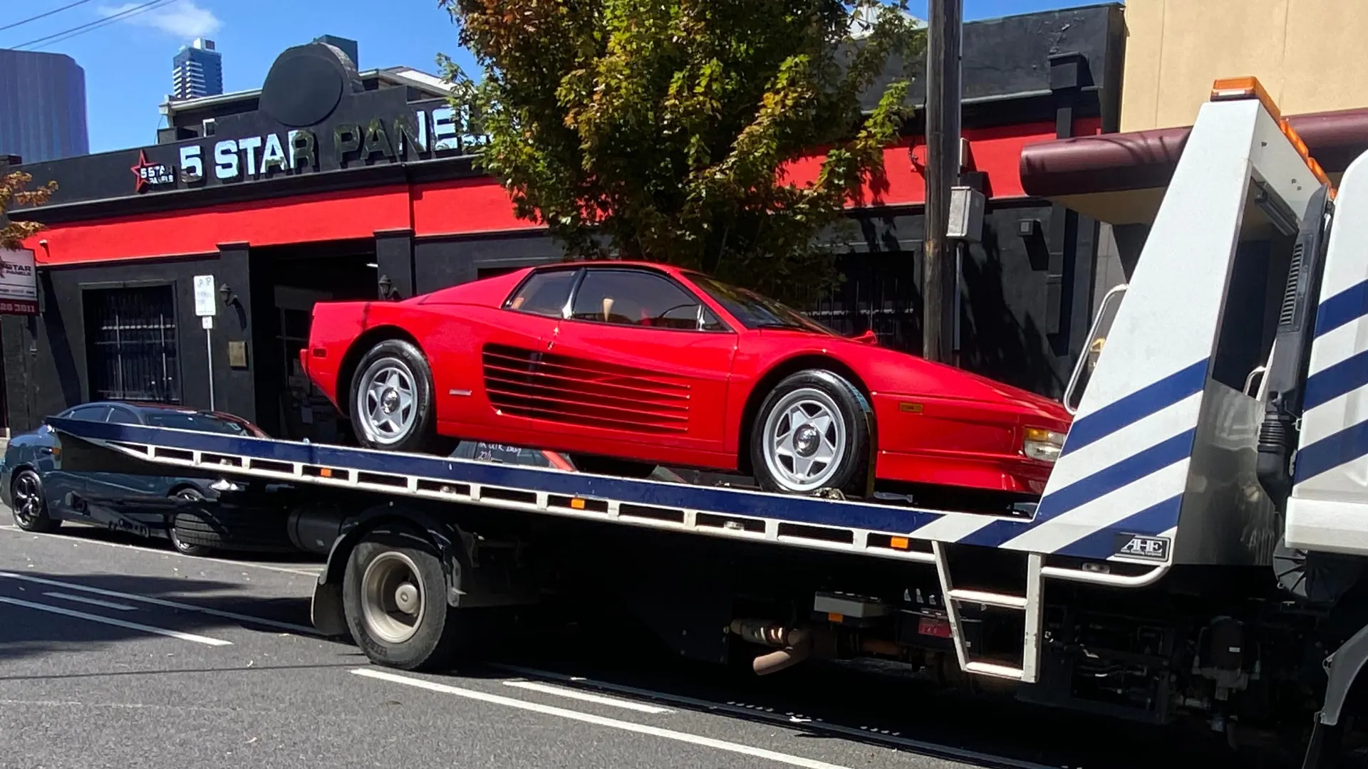 Red Ferrari Testarossa loaded on the All Over Towing tilt tray outside a Melbourne panel shop