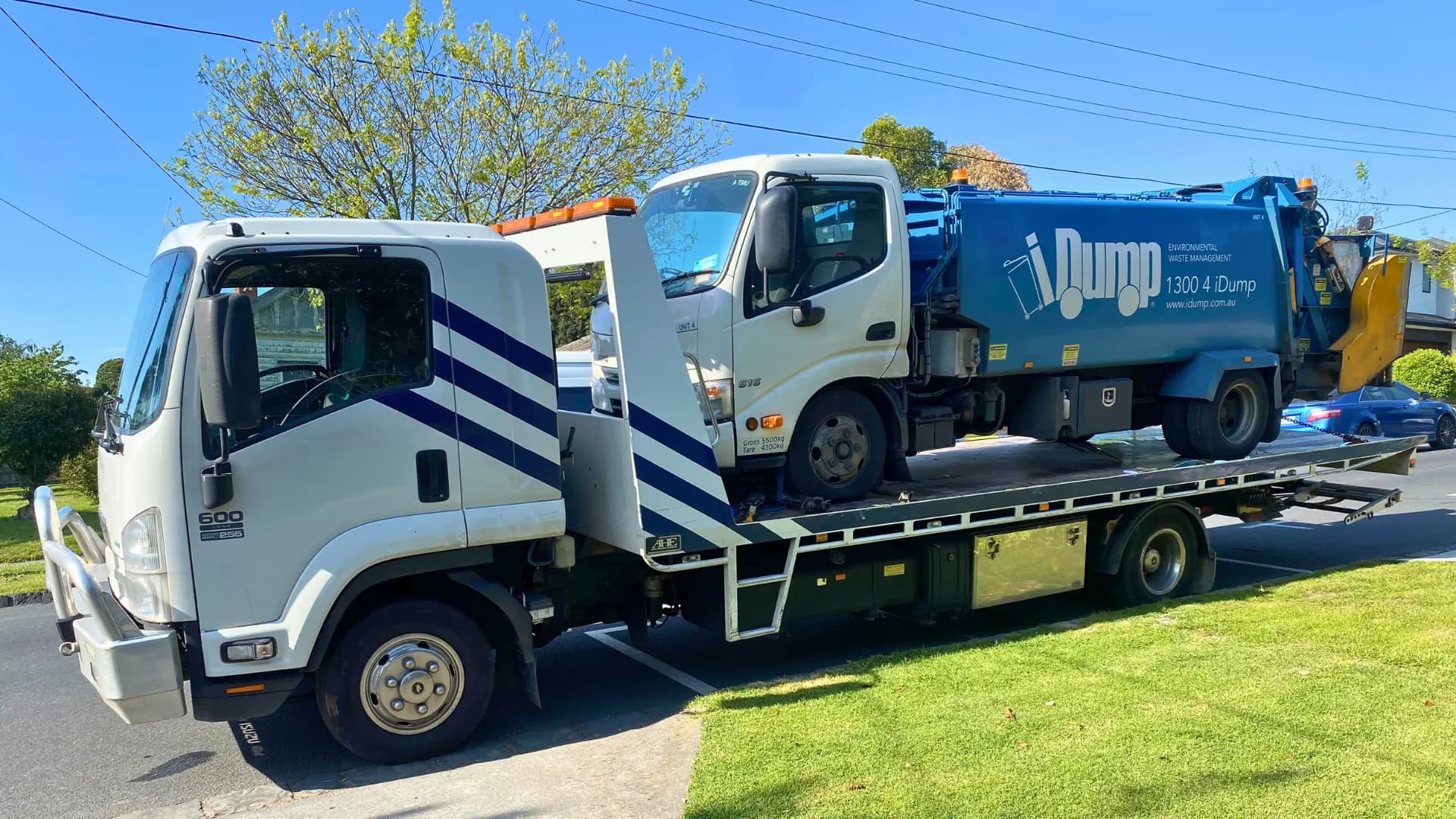 Blue iDump work truck loaded on the All Over Towing tilt tray