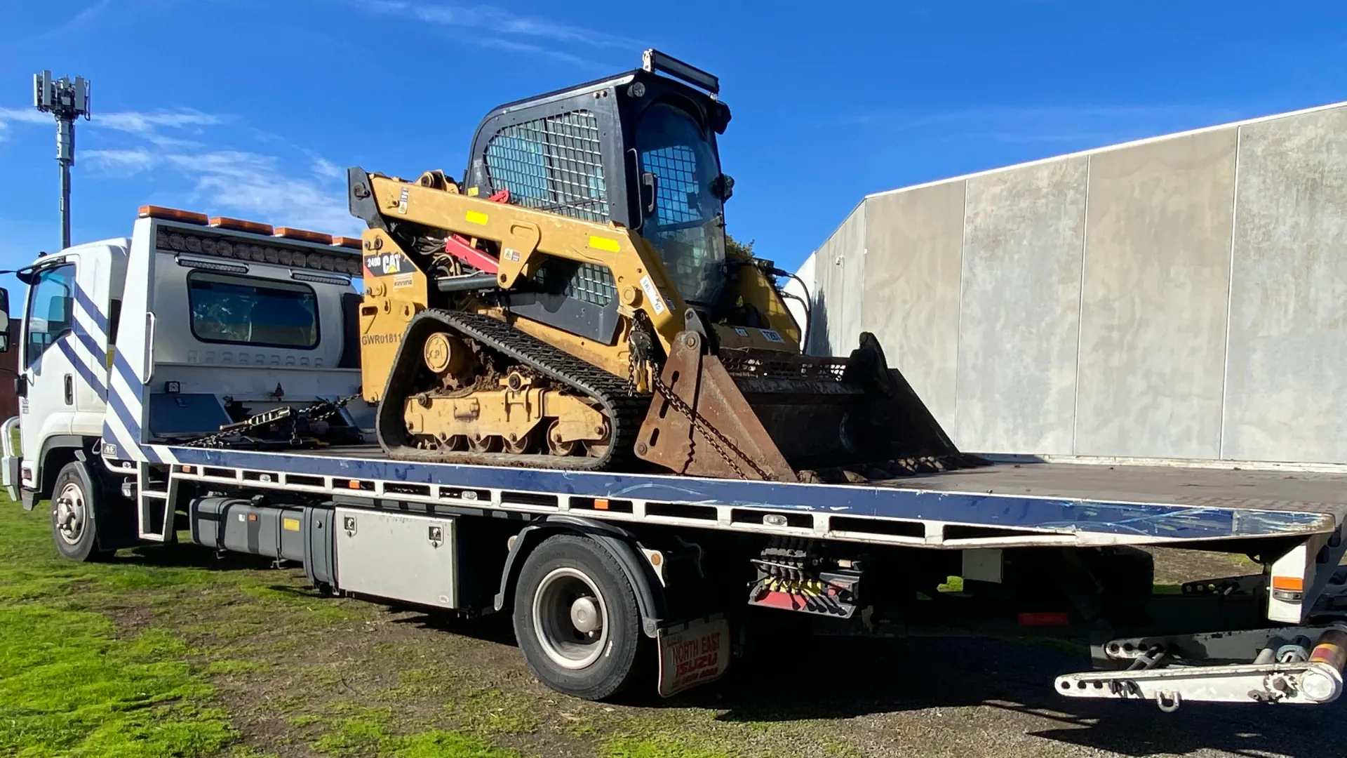 Tracked mini excavator secured on the All Over Towing tilt tray at a Melbourne work site
